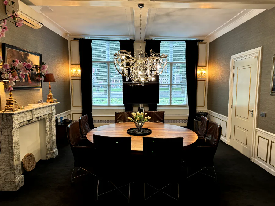 Boardroom met ovale tafel, kroonluchter en marmeren schouw