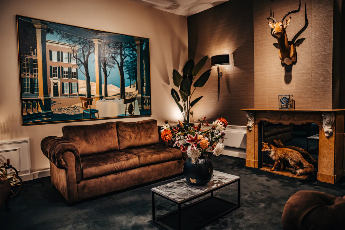 De salon aan het Lange Voorhout: chesterfield-bank, schilderij en marmeren schouw